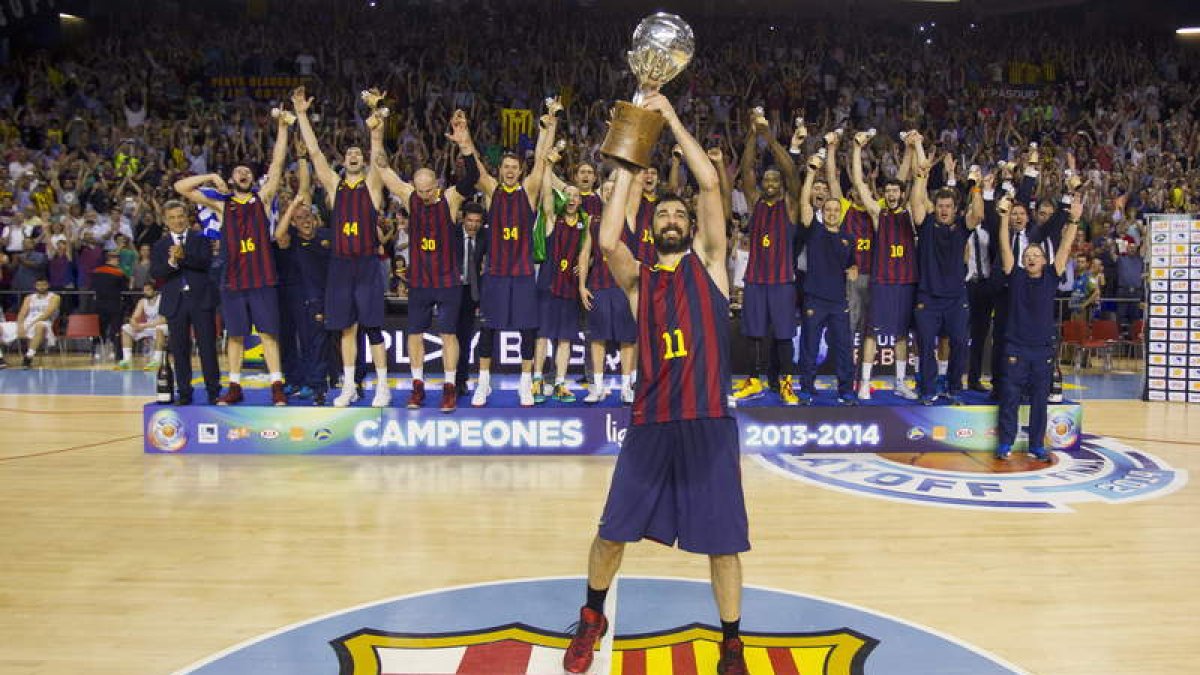 Navarro, capitán del Barcelona, levanta la copa que acredita a su equipo como campeón liguero.
