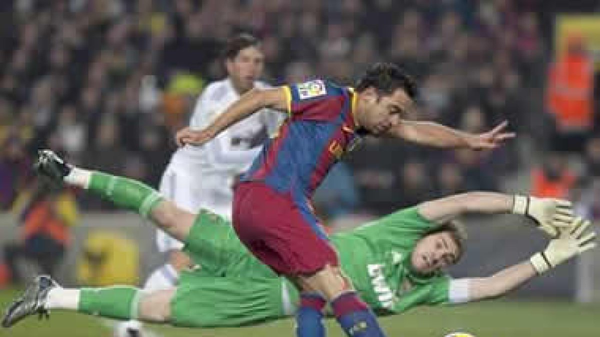 Xavi Hernández trata de superar la salida de Iker Casillas durante un lance del partido.