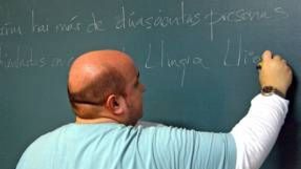 Un profesor de lengua leonesa escribe en la pizarra en una de sus clases