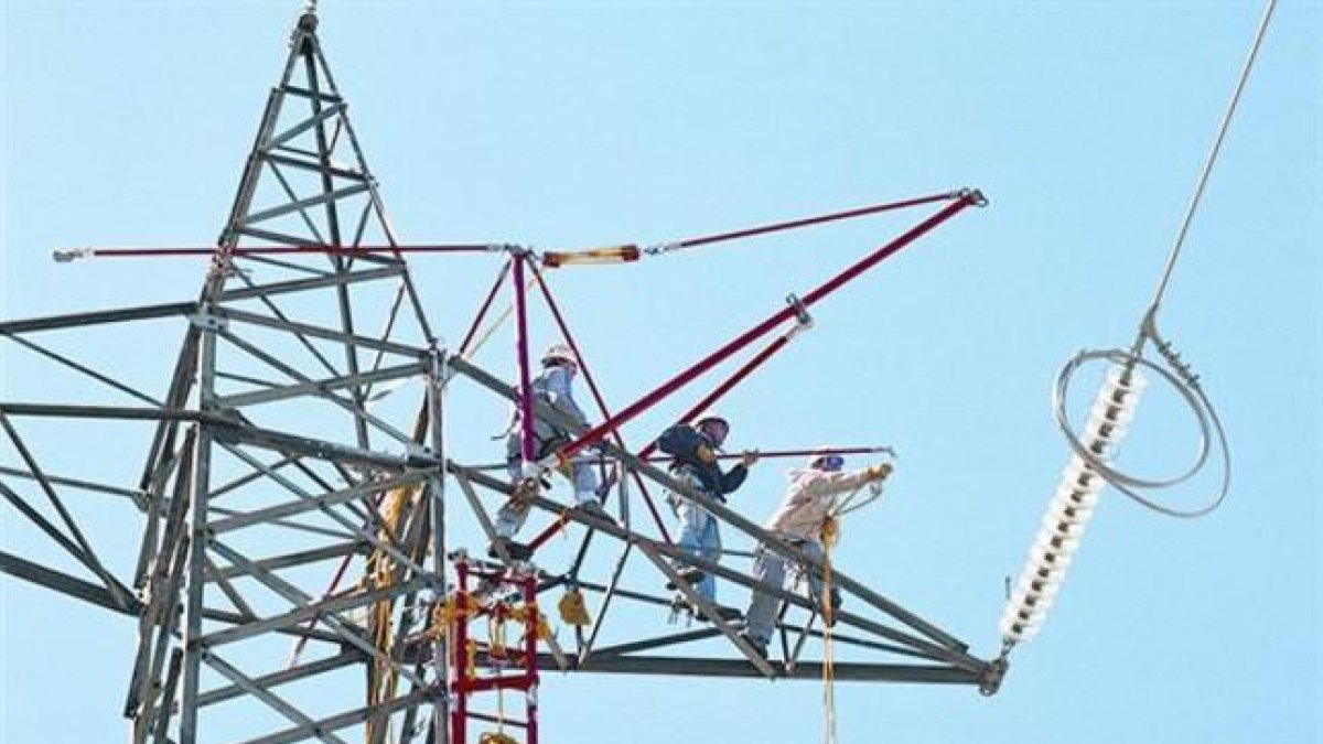 Un grupo de trabajadores preparan la sustitución del tendido de electricidad de una torre de alta tensión.