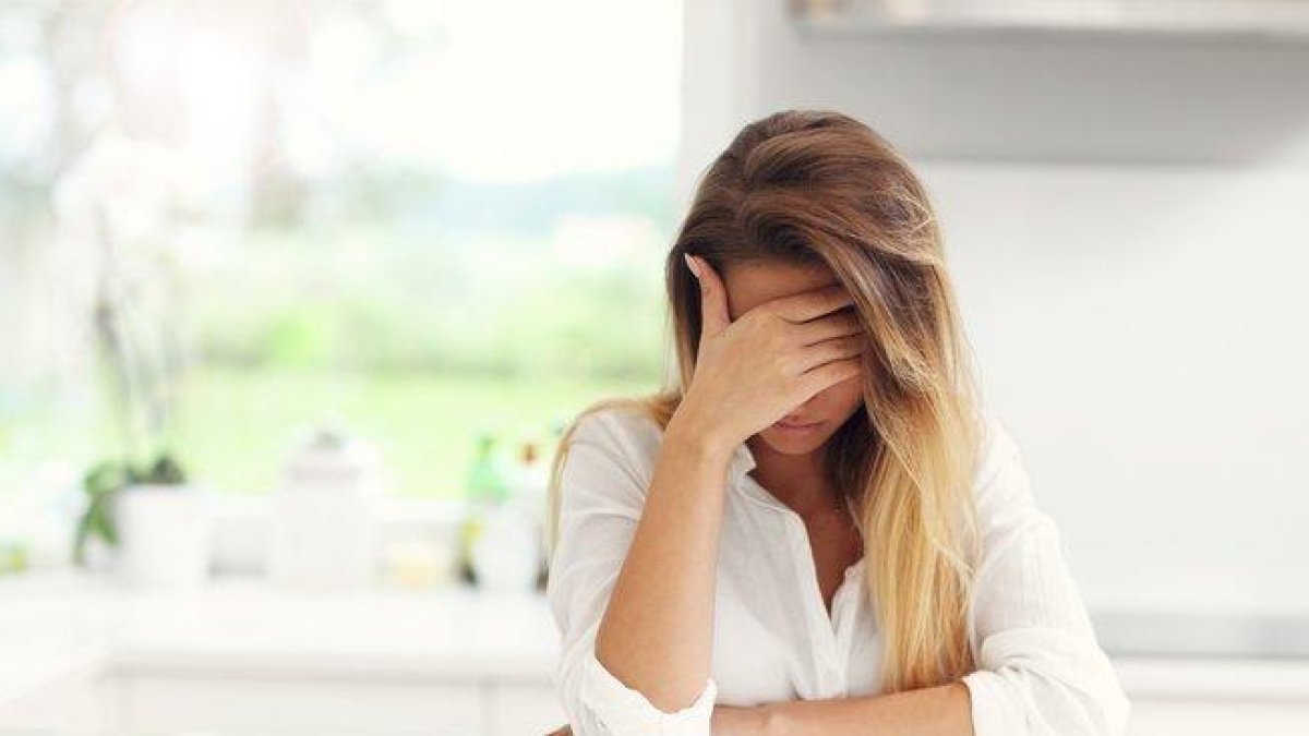Mujer triste con la cara tapada.