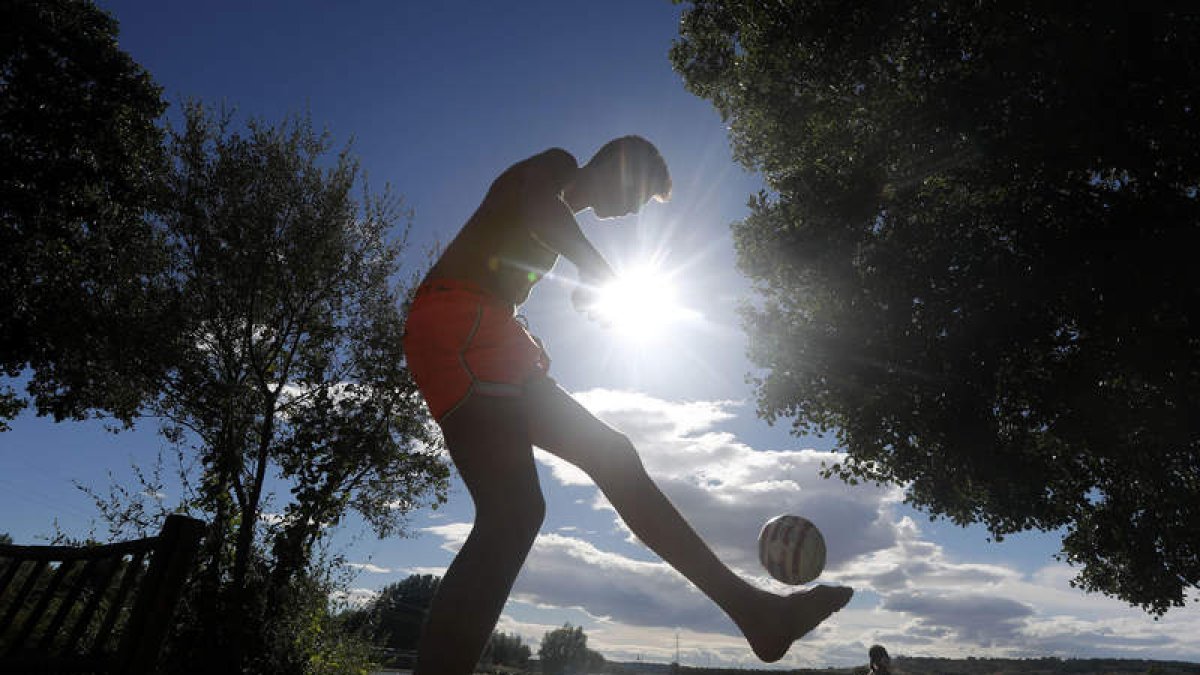 Un joven juega a la pelota al lado del río en Santa Marina del Rey, ayer. JESÚS F. SALVADORES