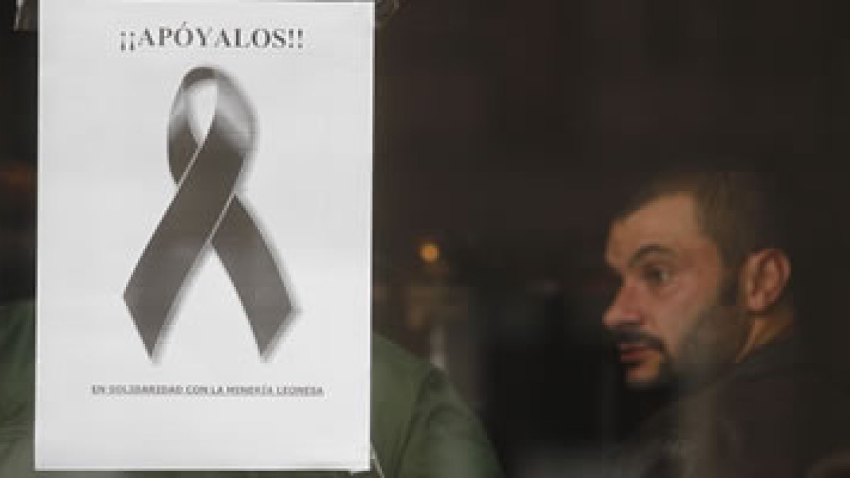 Cientos de carteles con lazos negros cuelgan en escaparates y edificios de Villablino para reclamar