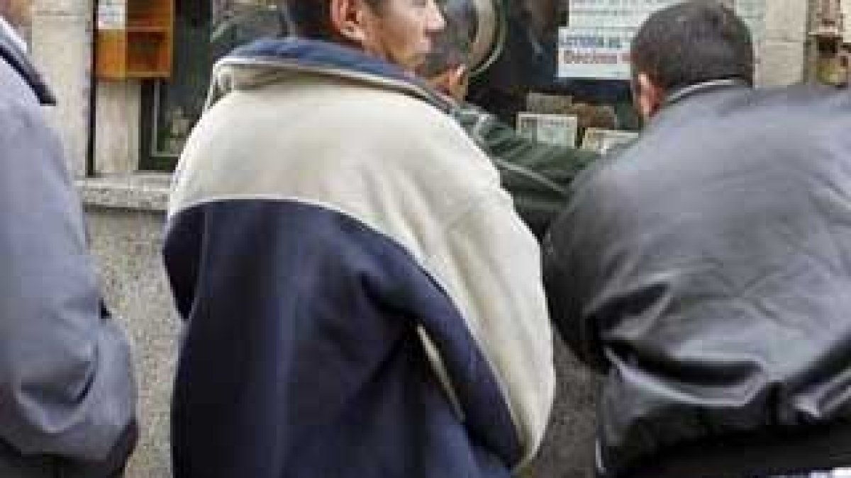 Varias personas hacen cola hoy ante una administración de lotería.