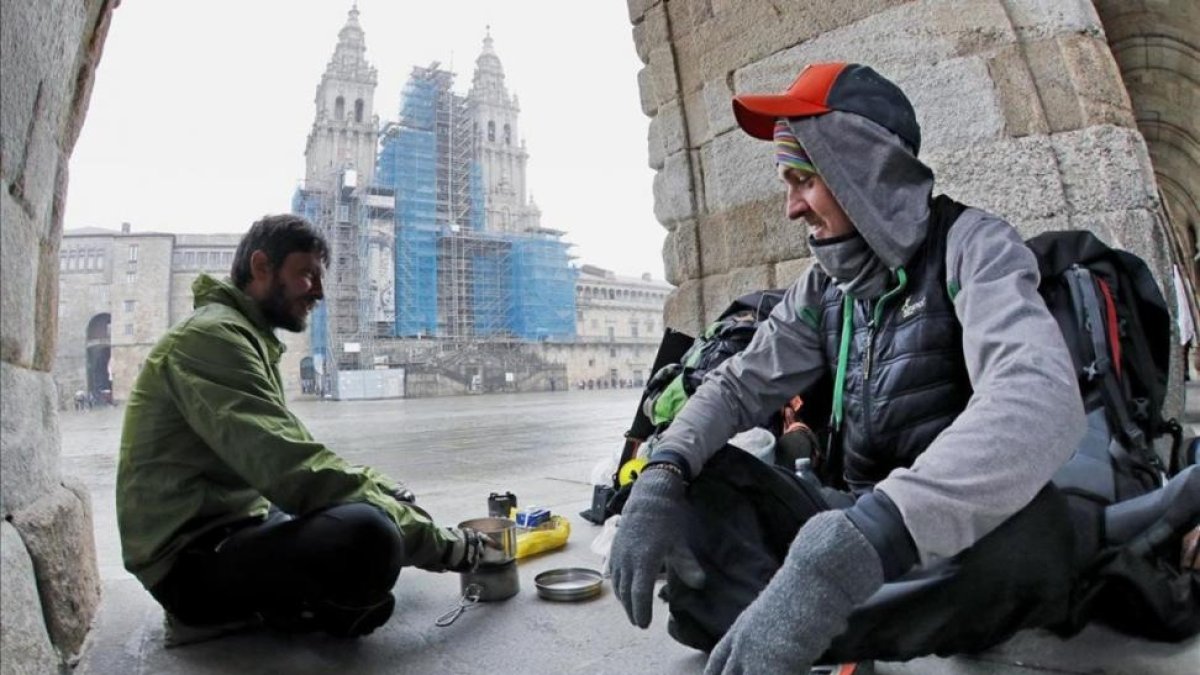 Dos peregrinos checos que llegaron desde Bordeaux se cobijan del frío con un hornillo debajo de los arcos del palacio de Raxoi, en la plaza de Obradoiro.