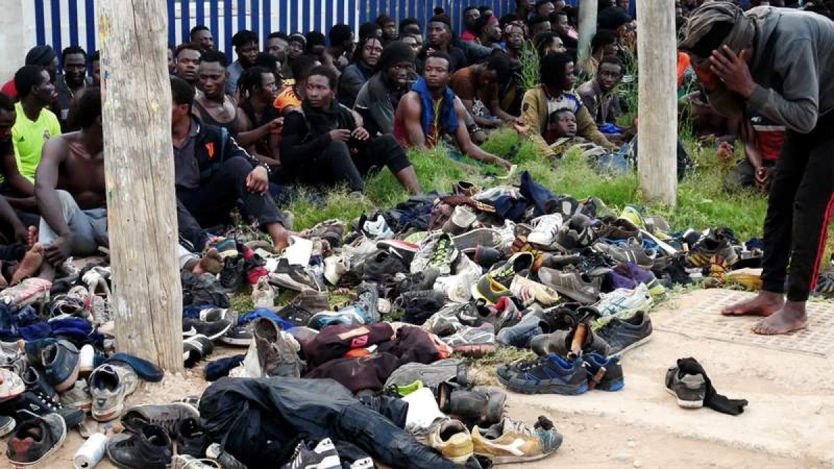 Un grupo de subsaharianos descalzos aguarda la decisión policial tras conseguir saltar la valla fronteriza de Melilla. PAQUI SÁNCHEZ