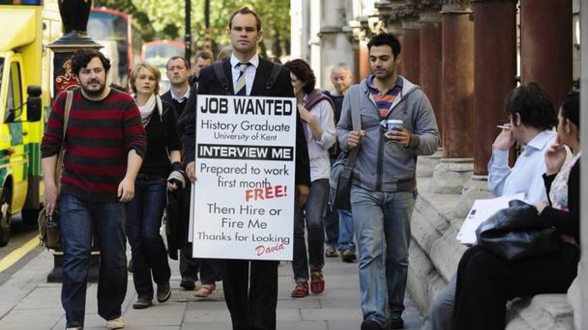 Un licenciado universitario en paro lleva una pancarta en la que pide trabajo, en Londres.