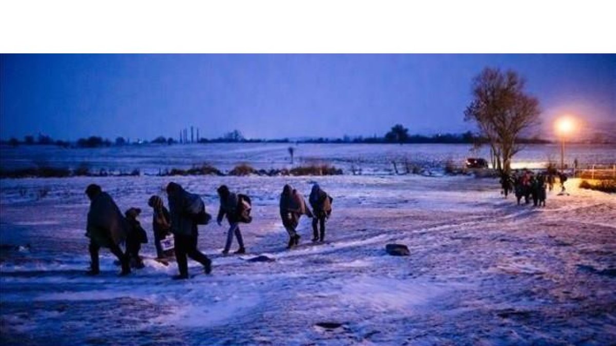 Migrantes y refugiados caminan por un campo cubierto de nieve tras cruzar la frontera de Macedonia con Serbia, cerca de la población de Miratovac, este domingo.