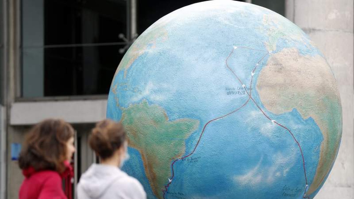 Dos personas observan una bola del mundo con sus océanos. LUIS TEJIDO