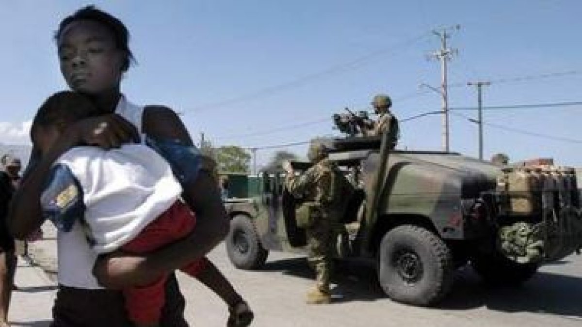 Una joven con su hijo camina con los brazos en alto ante la policía tras el terremoto.