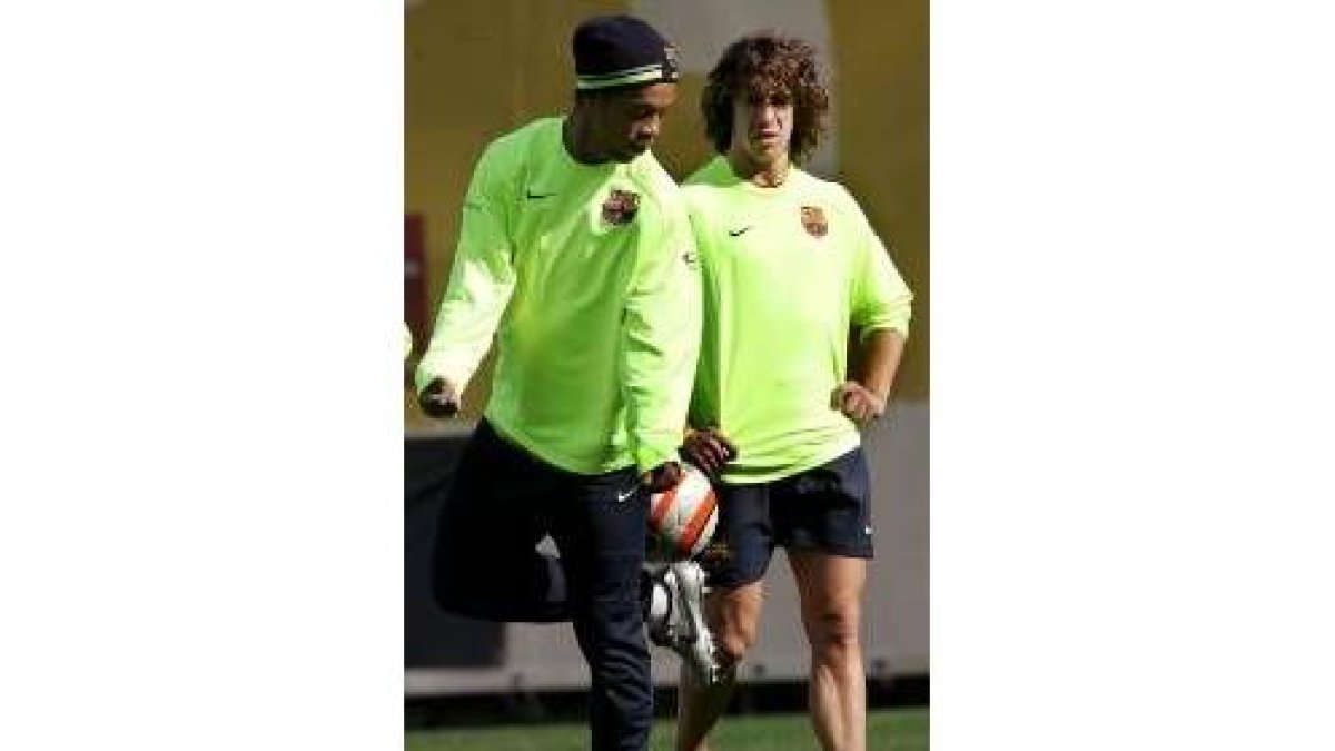Ronaldinho hace malabares con el balón ante la atenta mirada de Puyol
