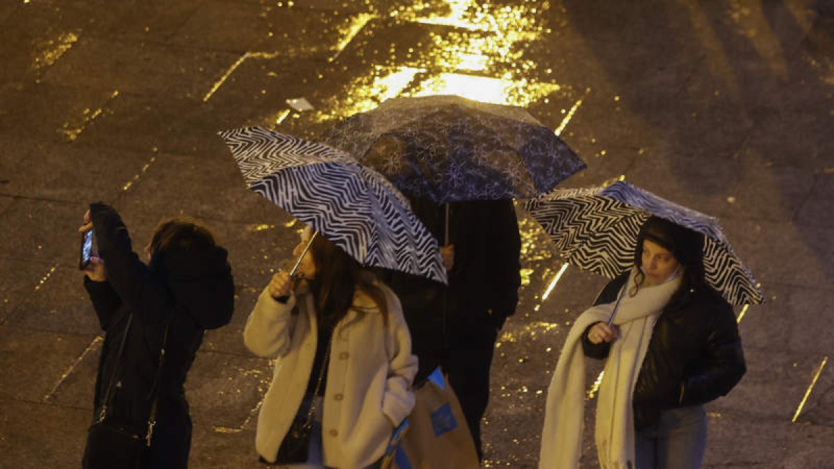 Jóvenes en la Puerta del Sol durante una tormenta. JAVIER LIZÓN
