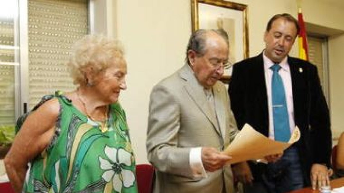 Ventura González, entre su mujer y Gaspar Cuervo, lee el diploma con su nombramiento.