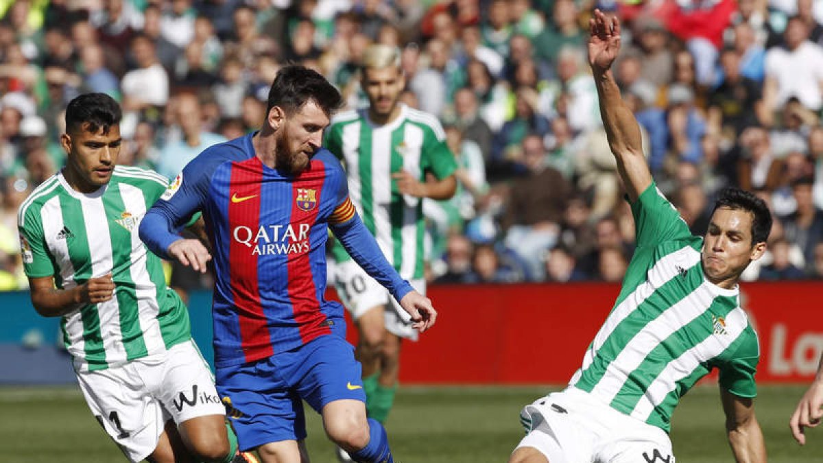El argentino Leo Messi intenta zafarse del férreo marcaje de dos jugadores del Betis. JULIO MUÑOZ