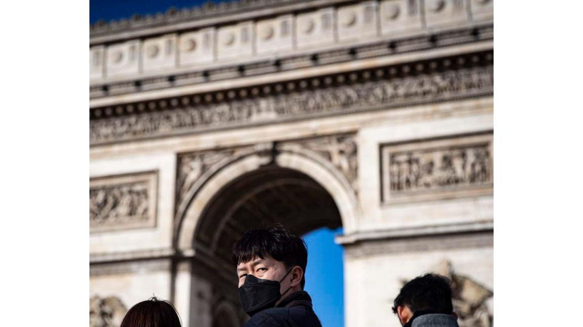 Un turista se protege frente al Arco del Triunfo de París.