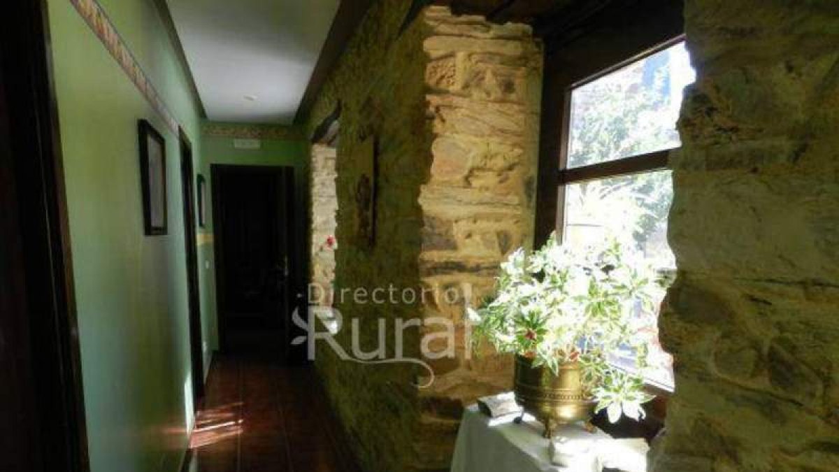 Pasillo que conduce a las habitaciones, fachada del viejo molino eléctrico de Luyego de Somaza convertido en alojamiento turístico y patio maragato con la mesa hecha de una de las piedras de moler.