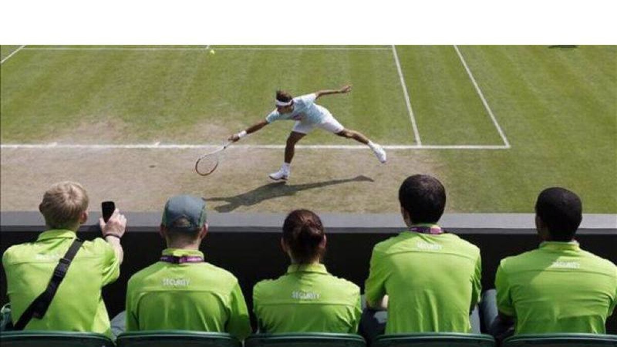 Personal de seguridad sigue el entrenamiento de Federer, este jueves en Wimbledon.