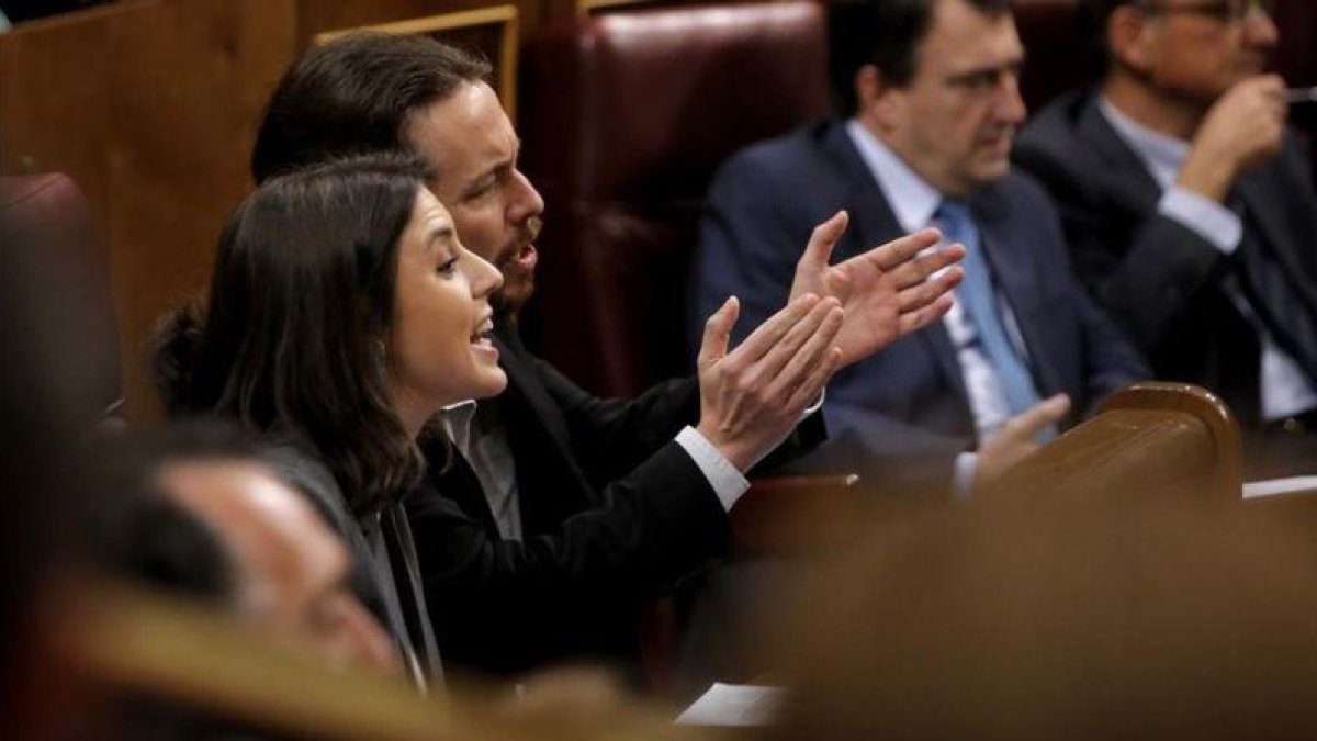 Irene Montero y Pablo Iglesias gesticulan durante la intervención de Soraya Sáenz de Santamaría en la sesión de control.