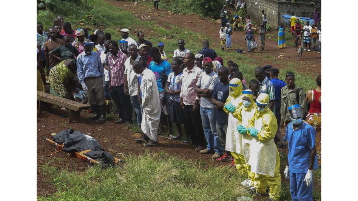 Unas personas rezan frente al cadáver de una víctima del ébola en Freetown, Sierra Leona.