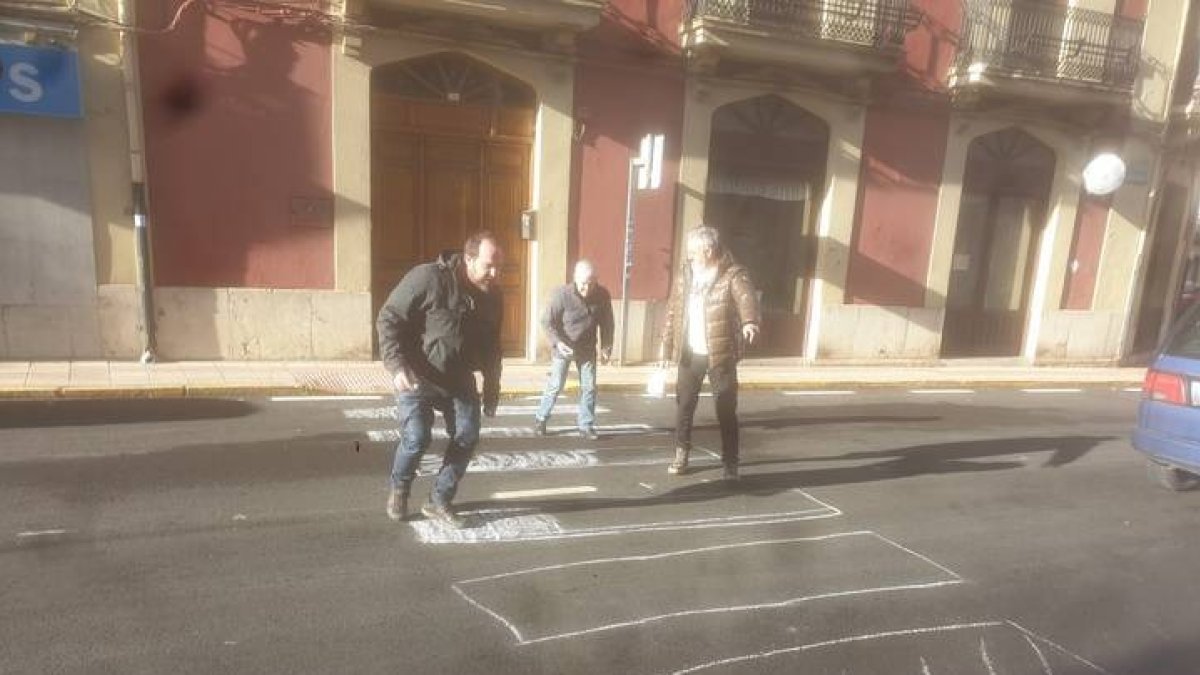 Un grupo de vecinos de Cistierna pintando con tizas los pasos de peatones. CAMPOS