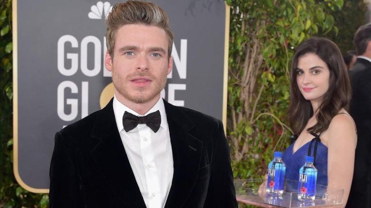 Richard Madden posa en un photobomb de la gala con la chica del agua Fiji de fondo.