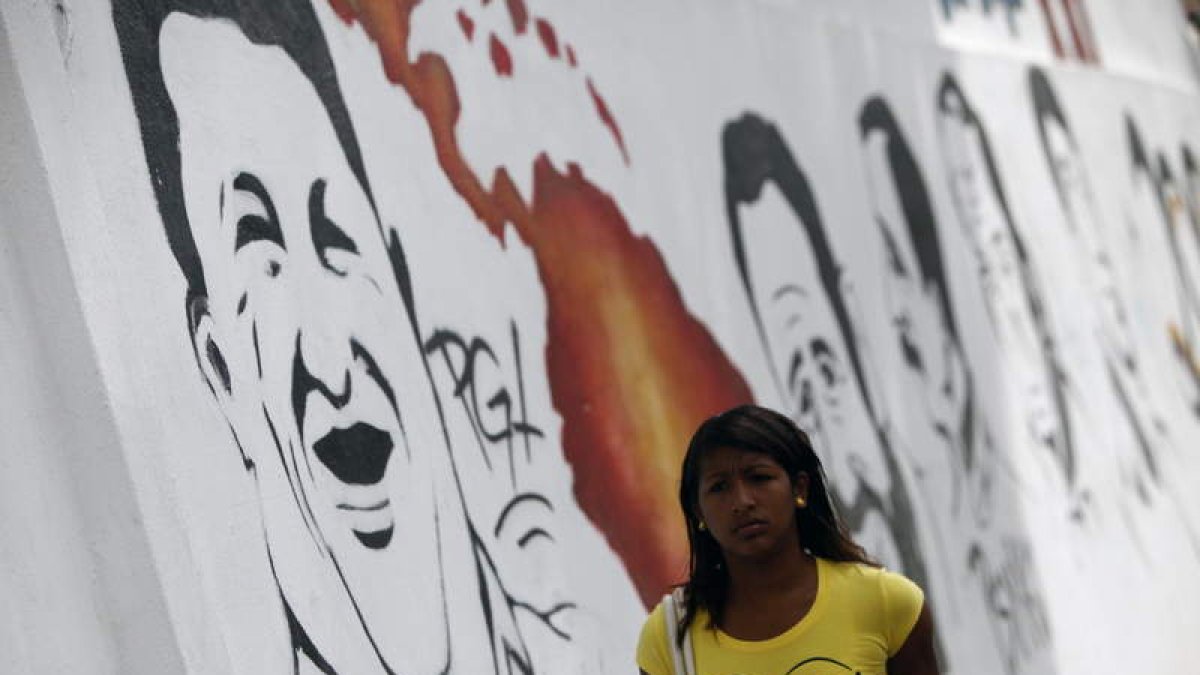 Una mujer camina junto a un grafiti alusivo al presidente venezolano, Hugo Chávez.