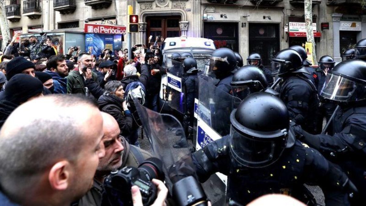 Manifestantes forcejean con mossos ante la Delegación del Gobierno en Cataluña.