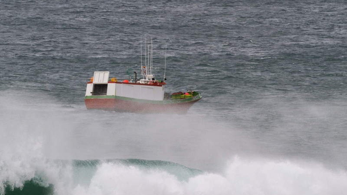 Un barco pesquero faena cerca de la costa.