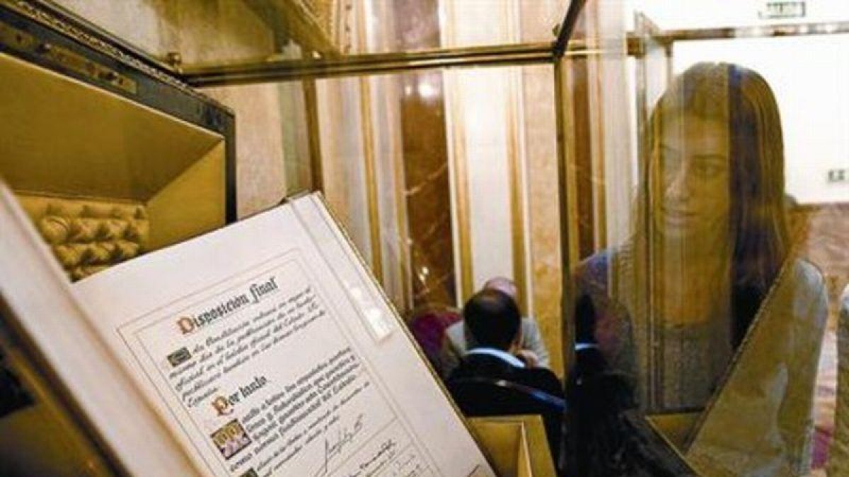 Una empleada del Congreso de los Diputados contempla, ayer, el ejemplar único del texto original de la Constitución, firmado por el Rey y los presidentes de las dos cámaras legislativas durante la sesión solemne que tuvo lugar el 27 de diciembre de 1978.