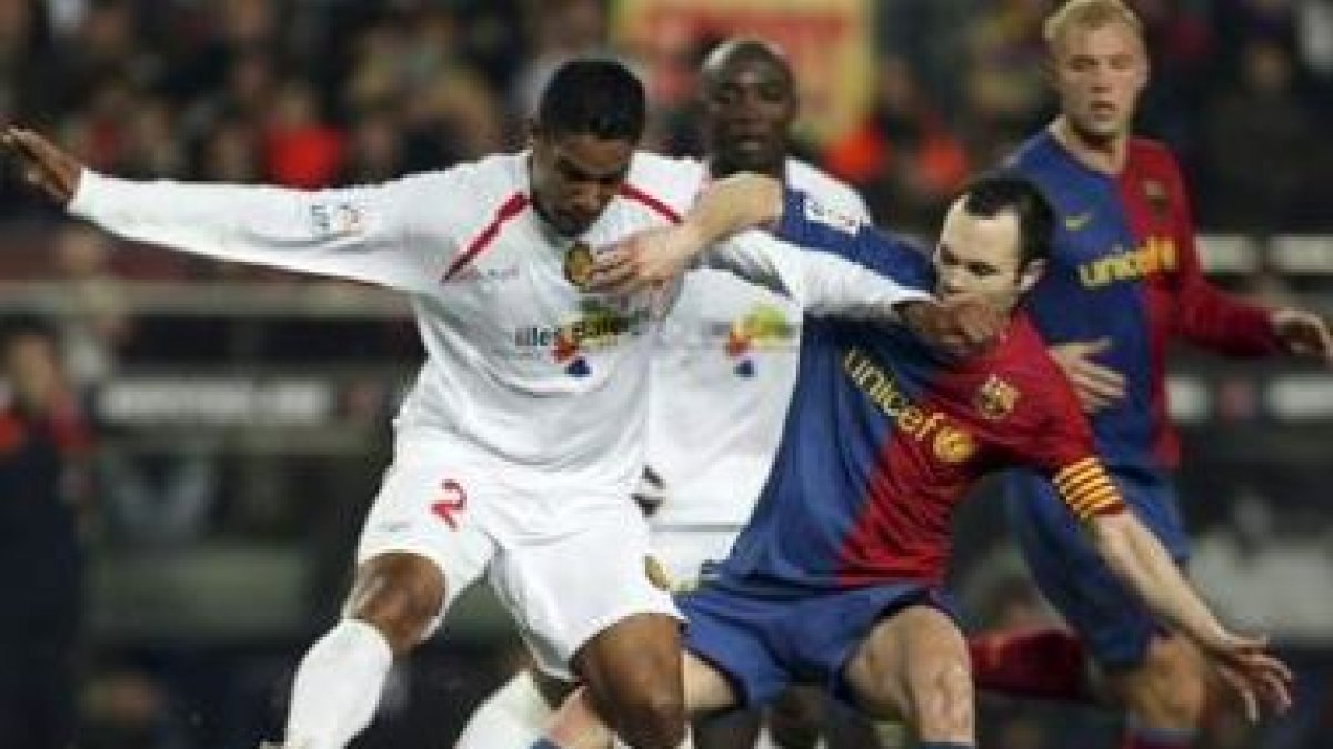 El centrocampista brasileño del Mallorca, Cléber Santana, pugna por el balón con Iniesta