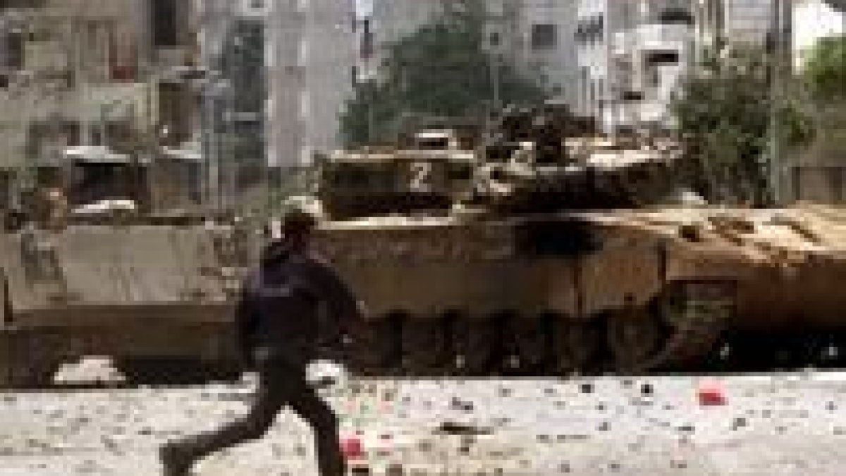 Un joven palestino lanza piedras contra tanques del Ejército israelí, ayer, en Gaza