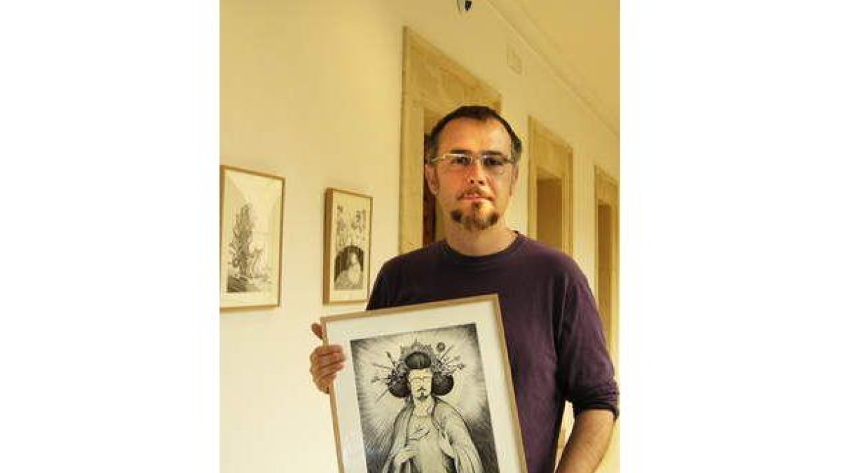 El artista leonés Karlos Viuda porta una de las obras que expone en la Casa de Carnicerías.