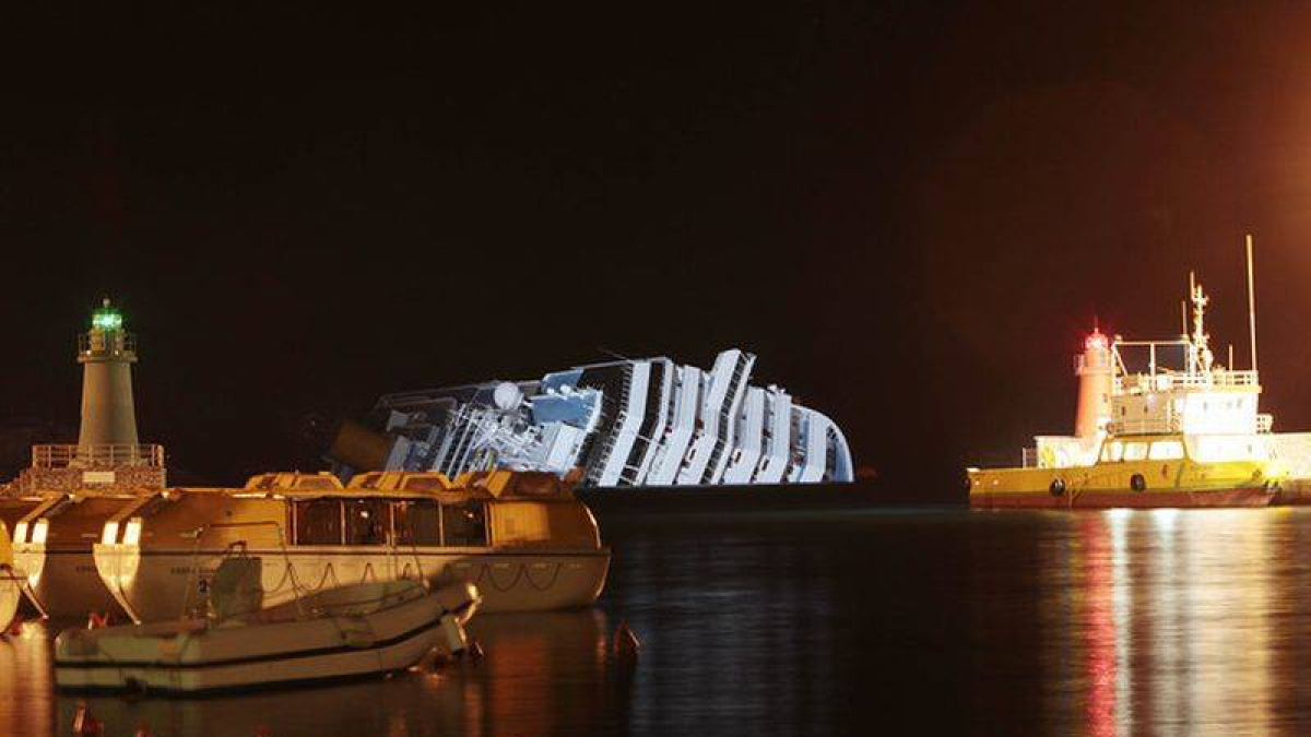 Dos barcos de rescate trabajan junto al 'Costa Concordia', totalmente ladeado, la pasada noche.