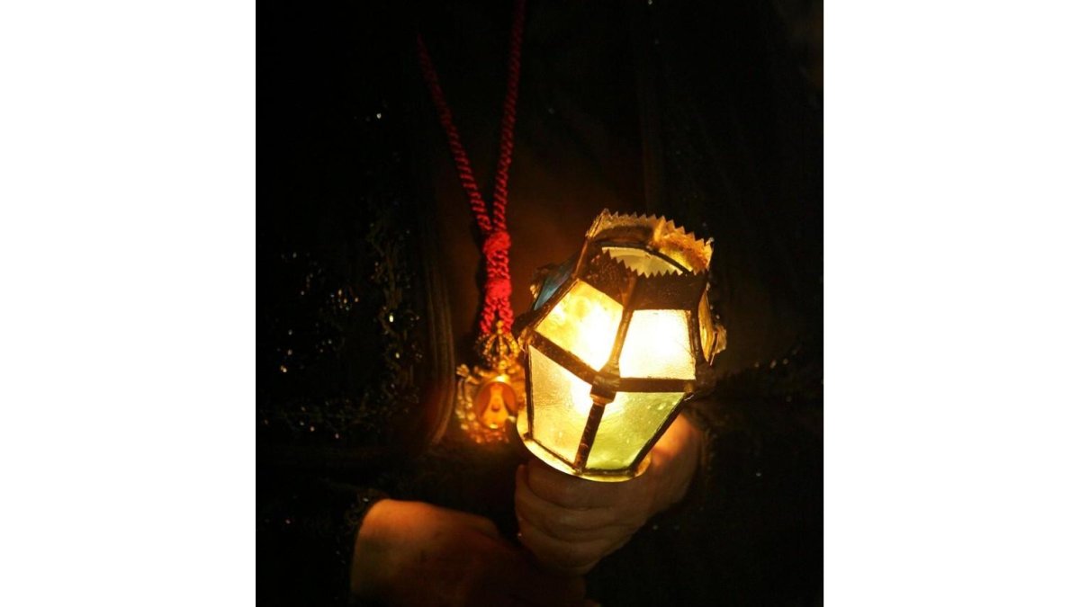 Una mujer con una vela en una procesión de Semana Santa en León