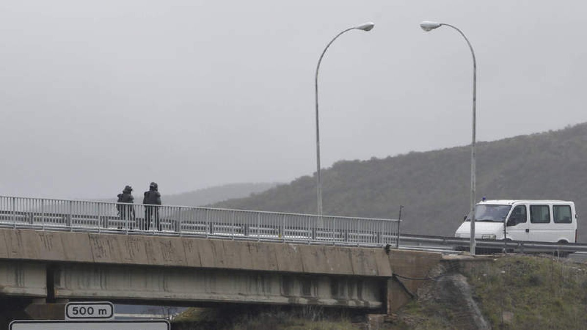 Dos antidisturbios se dirigen a una furgoneta policial sin distintivos en las inmediaciones del peaje de La Magdalena.