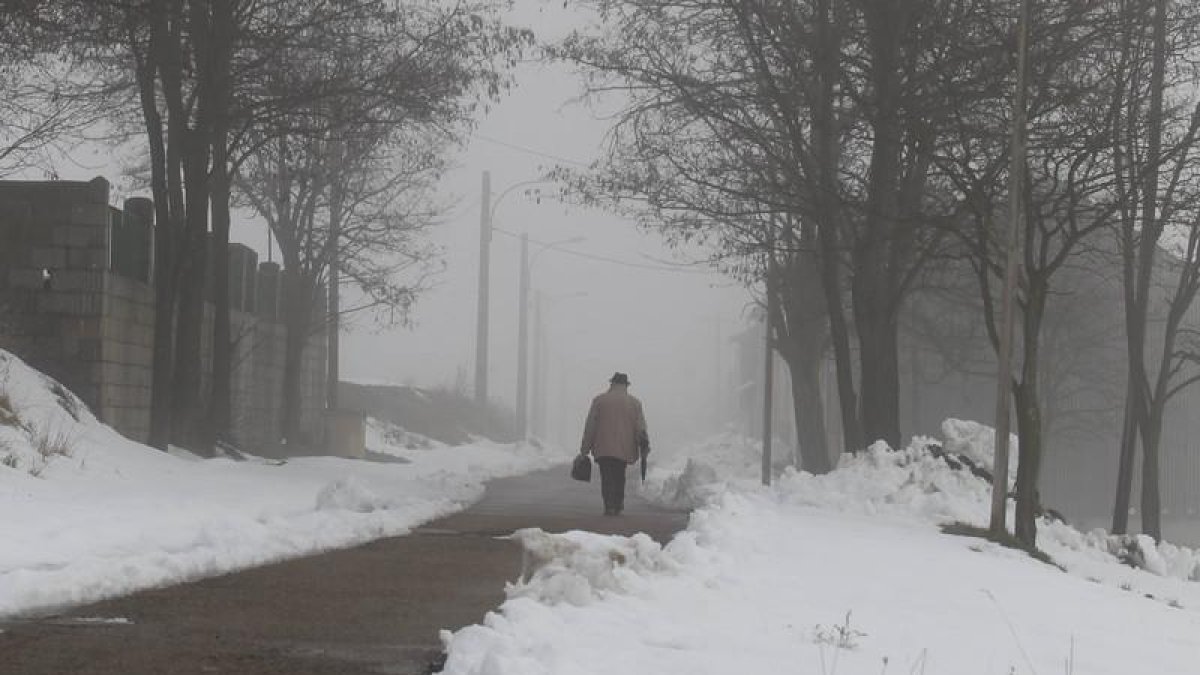 Un hombre camina por una carretera nevada en León.