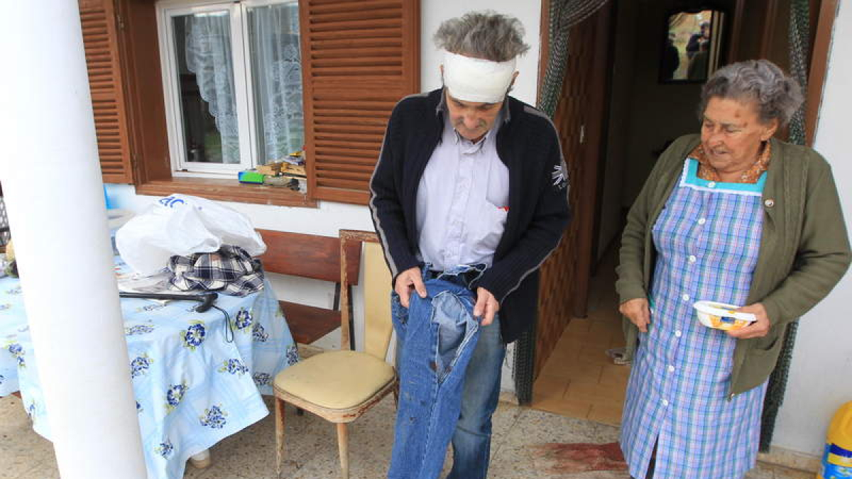 Tomás Martínez, con la cabeza vendada, enseña el pantalón roto y ensangrentado junto a su madre.