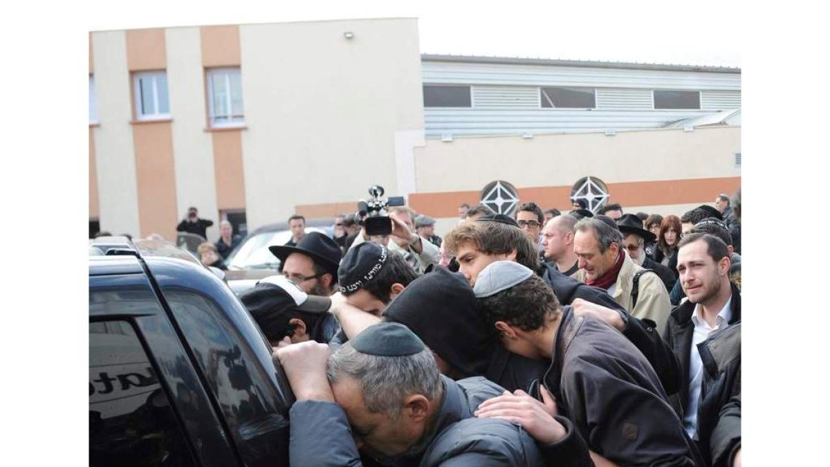 Decenas de personas siguen al coche fúnebre de uno de los fallecidos en Toulouse.
