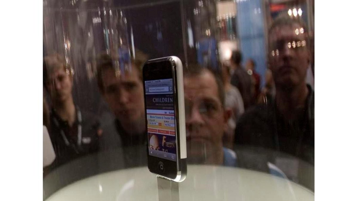 Varios aficionados a las últimas tecnologías contemplan un móvil de la marca Apple.