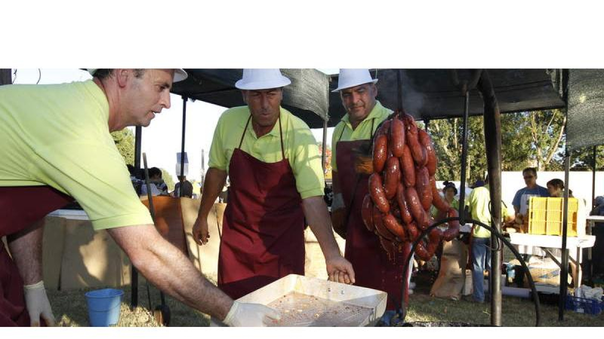 Varios voluntarios preparan el chorizo al vino prieto picudo en una edición pasada de la fiesta de Valdevimbre.