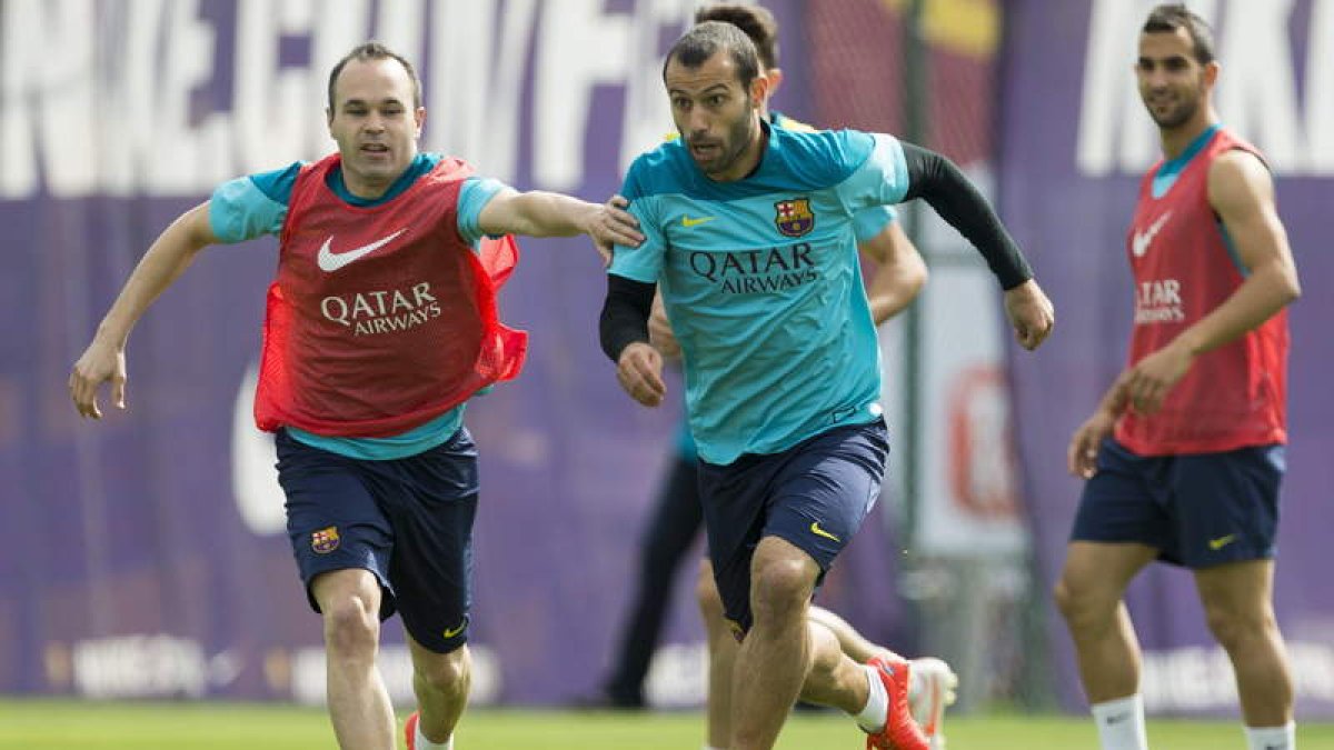 Iniesta y Mascherano juegan con un balón de rugby durante el entrenamiento del Barça.