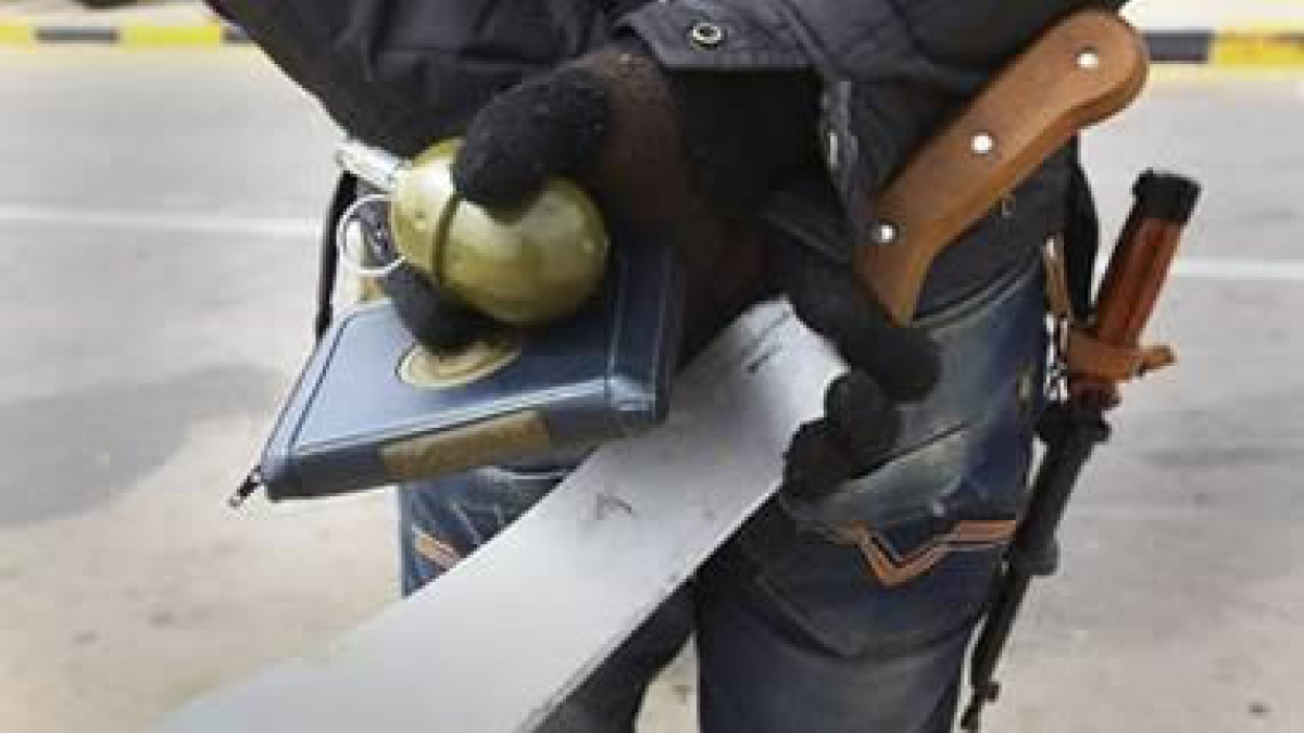 Un soldado de la oposición rebelde libia sostiene en sus manos un Corán, un machete y una granada