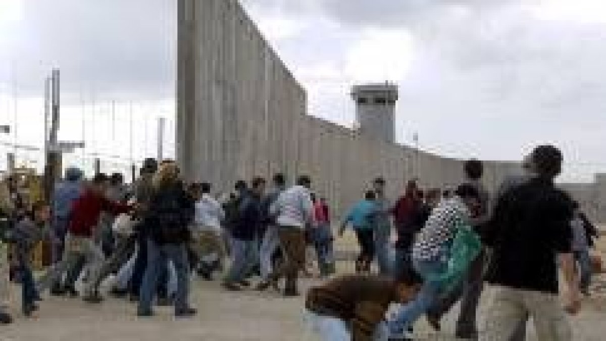 Varios manifestantes palestinos cruzan una zona del Muro de Cisjordania en obras