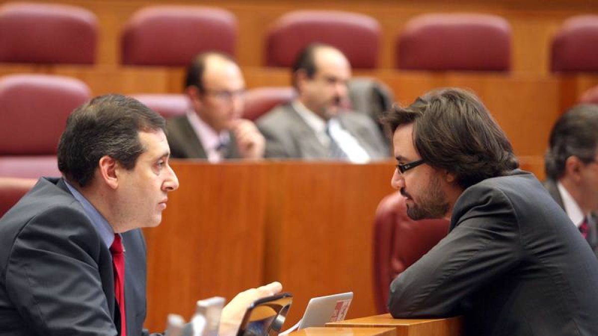El procurador popular Alfonso García Vicente (D) conversa con el socialista Miguel Ángel Fernández Cardo en el Pleno de las Cortes