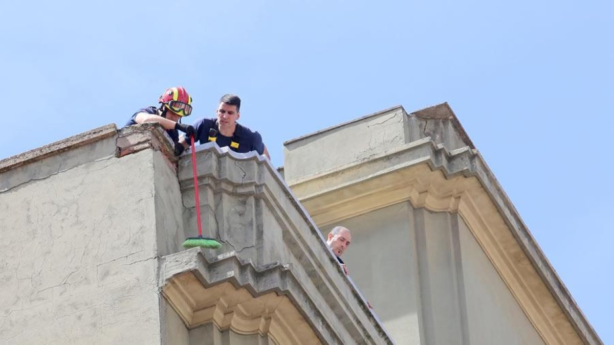 Bomberos de la capital durante la operación de retirada de cascotes y revisión de la fachada desde la que se desprendieron.
