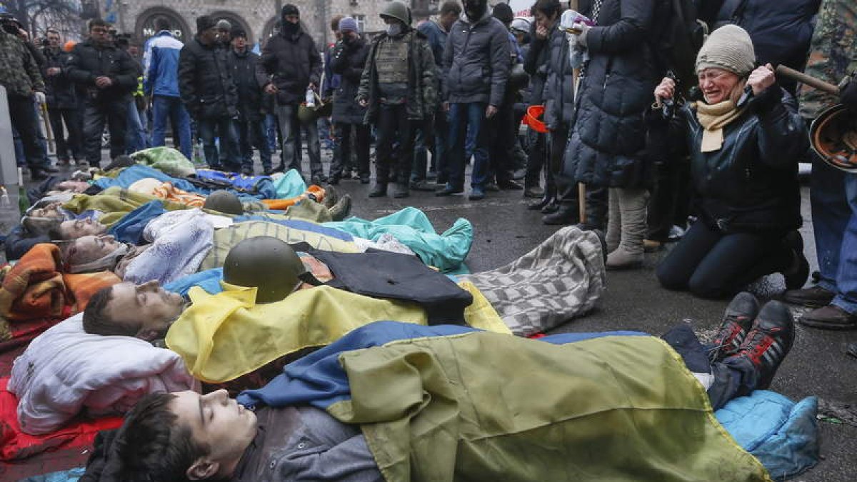 Decenas de ucranianos muestran sus respetos a un grupo de personas muertas durante los disturbios que tuvieron lugar ayer en Kiev.