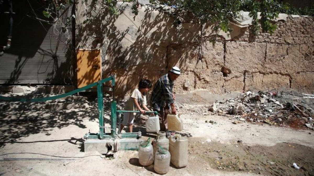 Un chico llena garrafas de agua en Damasco, Siria.