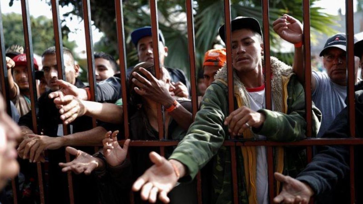 Los inmigrantes esperan una ración de comida en un refugio en Tijuana.