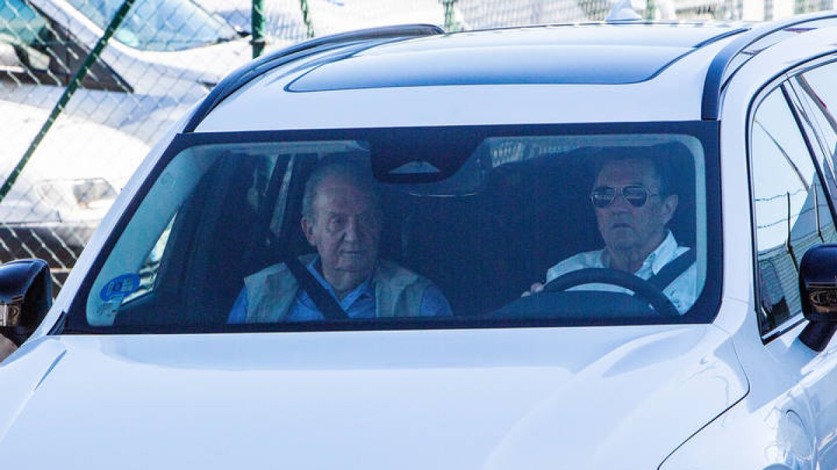 El rey emérito, Juan Carlos de Borbón, tras ser recibido por su amigo Pedro Campos (d) en el aeropuerto de Vigo. SALVADOR SAS