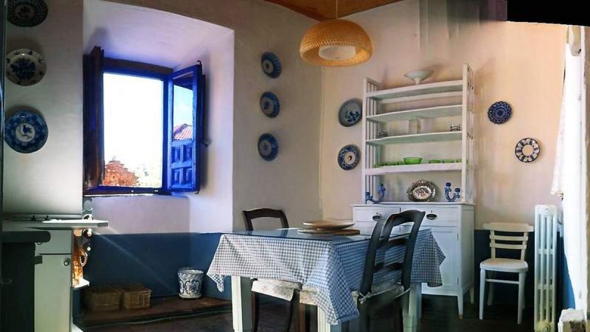 La cocina con su horno de adobe, uno de los dormitorios y otra parte de la cocina decorada con un árbol pintado a mano.